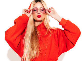 Portrait of young beautiful hipster bad girl in trendy red summer hoodie and earring in her nose.Sexy carefree smiling blond woman posing in studio.Positive model having fun.Isolated on white