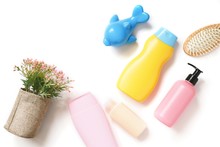 Flat Lay Photo Shampoo Bottle, Shower Gel, Liquid Soap, Hair Balm, Flowers And Toy Dolphin On A White Background
