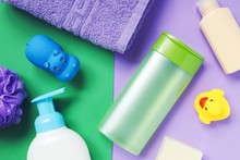 Flat Lay Photo Shampoo, Liquid Soap, Purple Towel, Sponge And Rubber Toys. Baby Care Cosmetic Products