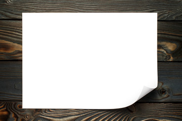 Sticker - Blank paper sheet with curved corner on dark wooden background