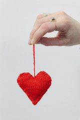 Wall Mural - Hand made knitted heart on white wooden background. Valentine's day card with woolen heart and free space. Romantic sign.