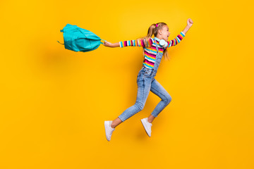 Wall Mural - Yeah holidays begin. Full size profile side crazy schoolkid jump run hold blue backpack bag have headset wear striped sweater denim jeans isolated over bright shine yellow color background