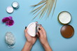 Woman's hands holding jar with cream over blue table with cosmetic products