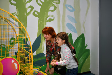 Wall Mural - beautiful little girl with her grandmother plays children's games in the children's play area