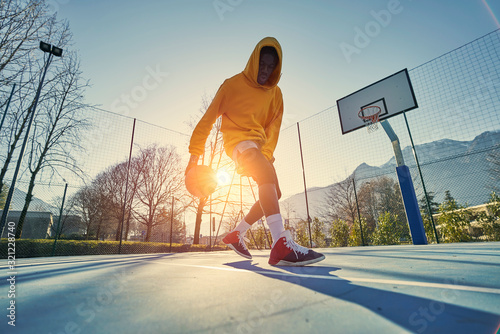 Cuadros en Lienzo Athletic black man showing his backetball skills on court outdoors