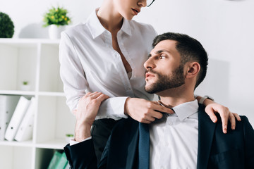 Wall Mural - cropped view of secretary with big breast hugging handsome businessman in office