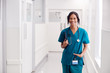 © Monkey Business - Portrait Of Smiling Female Doctor Wearing Scrubs In Hospital Corridor Holding Digital Tablet