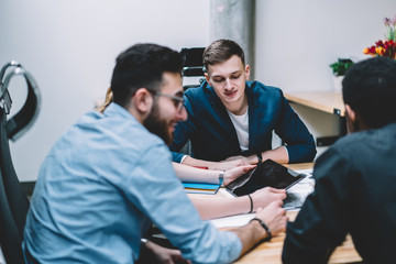 Wall Mural - Young man sitting amidst colleagues in meeting room