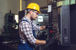 © zorandim75 - Industry Worker entering data in CNC machine at factory.