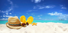 Concept Summer Beach Holiday. Beach Accessories - Straw Hat, Glasses, Starfish, Yellow Flip-flops On Sandy Tropical Beach Against Blue Sky With Clouds On Bright Sunny Day. Beautiful Colorful Image.