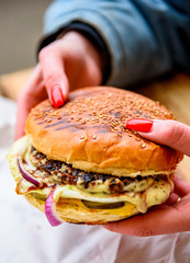 Woman hand holding a fresh burger before eating on street cafe