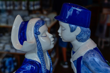 Wall Mural - Delft, the netherlands, august 2019. The couple kissing at a shop of the famous white and blue ceramics: a very appreciated and famous souvenir.