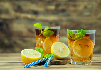 Wall Mural - Iced tea with lemon slices and mint on wood background