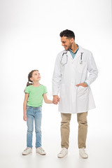 Wall Mural - Full length of kid and pediatrician smiling at each other and holding hands on white background