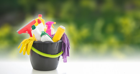 Wall Mural - Cleaning supplies in a bucket against blur green background.