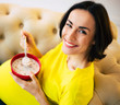 © My Ocean studio - Cereal breakfast for the future mom. Close-up photo of a happy pregnant woman sitting at home on a couch, eating healthy food and smiling.