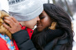 The guy kisses a young beautiful girl on the street in winter. Beautiful afro american woman hugs a man.