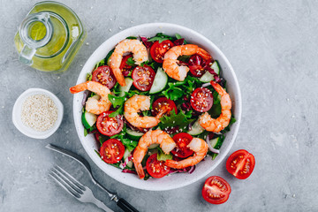 Shrimp salad with fresh green lettuce and radicchio leaves, cucumbers, tomatoes and sesame seeds.