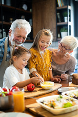 Wall Mural - happy grandparents with grandchildren making breakfast in kitchen
