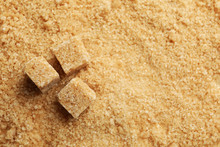 Brown Sugar Cubes On Sugar Background, Space For Text