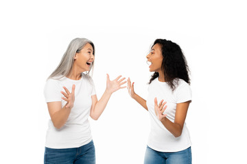 Wall Mural - excited multicultural women gesturing and looking at each other isolated on white