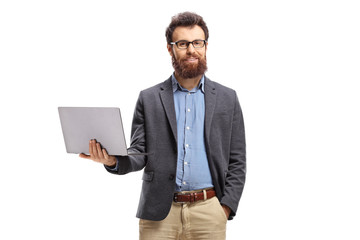 Bearded man standing with a laptop and smiling at the camera