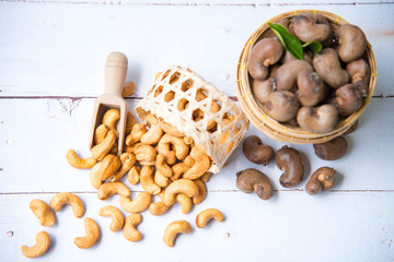 Roasted salted raw cashew nuts with Fresh cashew in spoon and  basket isolated on white wooden background,top view.
