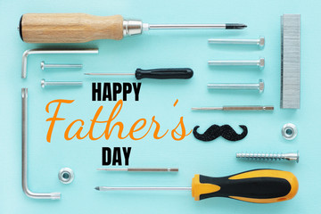 Greeting card of a happy father's day. screwdrivers, bolts, staples for a stapler, screws, nuts on a light blue background..