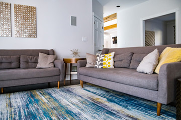 Mid century modern contemporary style living room den in a spacious open home with a vaulted ceiling and a pine wood ceiling and neutral gray couch and furniture