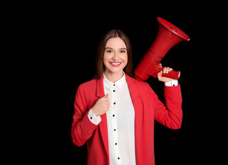 Young woman with megaphone on black background