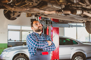 Wall Mural - Thoughtful mechanic examining car at the workplace