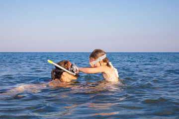 little girl playing with woman, both with diving glasses to snorkeling, in the water of Genoveses Beach, in Cabo de Gata Natural Park (Almeria, Andalusia, Spain)