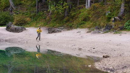 Wall Mural - young tourist hiker man walking at beautiful alpine lake lago di braies (pragser wildsee) in trentin