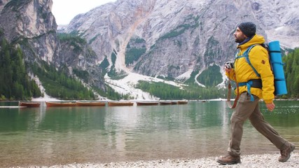 Wall Mural - young tourist hiker man walking at beautiful alpine lake lago di braies (pragser wildsee) in trentin