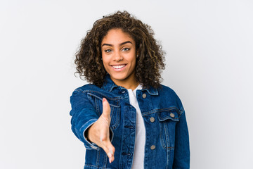 Wall Mural - Young african american woman stretching hand at camera in greeting gesture.