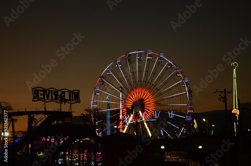 Cuadros en Lienzo rueda de la fortuna en la feria mientras cae el atardecer, juegos de fondo con l