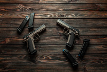 Modern Brown Guns On A Wooden Background. Pistol. Weapons For Sport And Self-defense Lie On The Table.