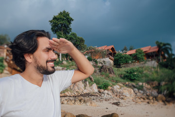 Wall Mural - Portrait of a male tourist on the beach on the background of Thai national houses