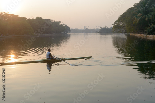 Individual Sports Speed Rower in Single scull crew rowing boat sliding racing shell on lake water oars in motion sitting sliding rigger seat doing exercise, fitness workout in sunset Tableau sur Toile