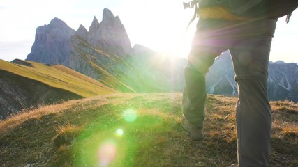 Wall Mural - young man hiking at seceda mountain arriving to peak at sunrise. backpack, yellow jacket, boots, bea