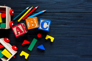 Wooden blocks with A B C letters, toys for creativity development on black background. Educational games for kindergarten, preschool kids.