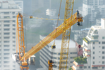 Aerial view of a construction site with building crew dissemble tower crane on a hazy day.