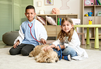 Canvas Print - Cute little children dressed as doctors playing with dog at home