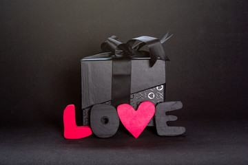 Wall Mural - Black gift box and red letters LOVE on dark background, copy space. Valentine's day, birthday romantic concept, greeting card.