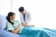 © Nipapun - Asian young male doctor with syringe to the arm of Asian young female patient  lying on bed at hospital/Healthcare and medically concept.
