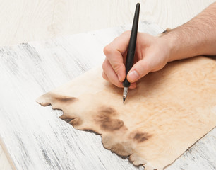 Male hand with pen writes on paper