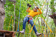 © Masarik - Young handsome boy teenager climbs up an obstacle in a rope park on summer vacation. Child on a tourist extreme crossed ferry.
