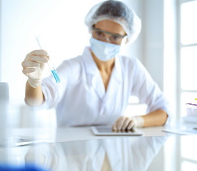 Professional female scientist in protective eyeglasses researching tube with reagents in laboratory. Concepts of medicine and research