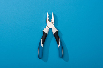 Wall Mural - Top view of pliers on blue surface with copy space