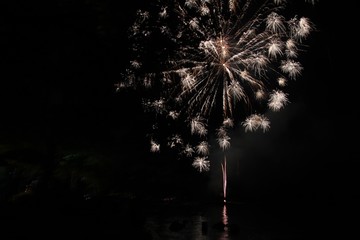 Burst of fireworks in the skies, with reflection in the water